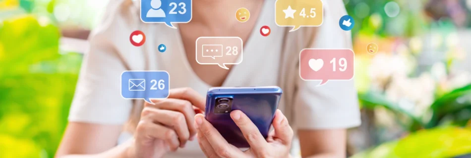 Asian woman uses a smartphone while marketing icons for social media interactions, like comments and likes, appear around her.